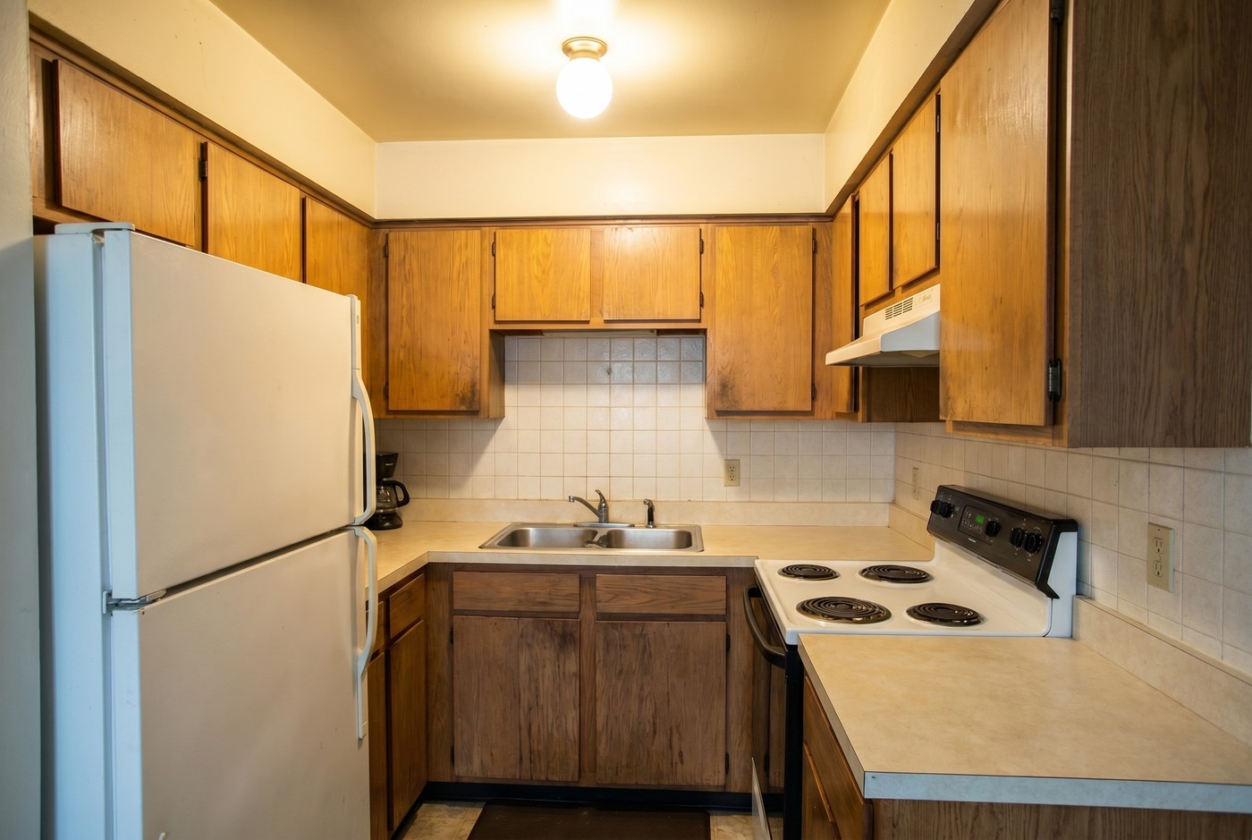 A bright, clean white kitchen with clear countertops and stainless appliances.