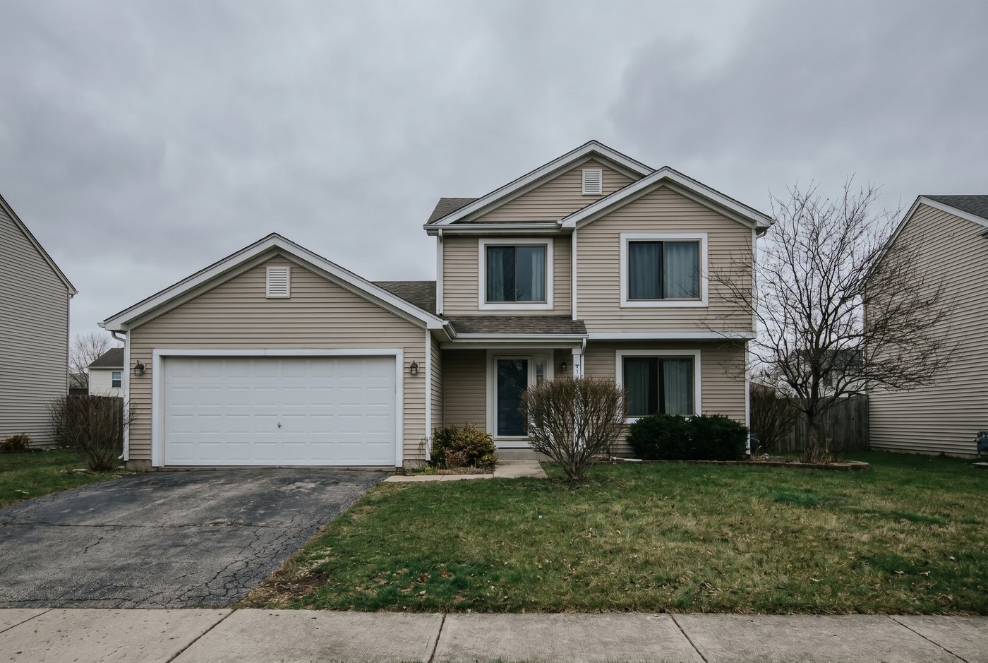 A suburban home photographed under a flat grey daytime sky.